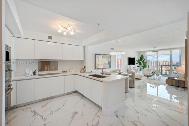 kitchen with white cabinetry, sink, pendant lighting, and kitchen peninsula