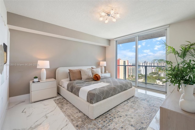 bedroom with marble finish floor, access to outside, expansive windows, a city view, and a textured ceiling