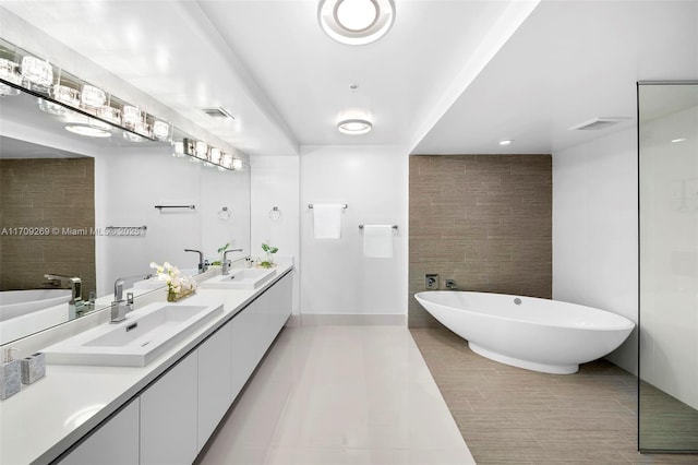 bathroom featuring vanity, a bath, tile patterned floors, and tile walls