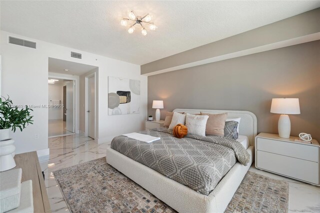 bedroom with marble finish floor, visible vents, a textured ceiling, and baseboards