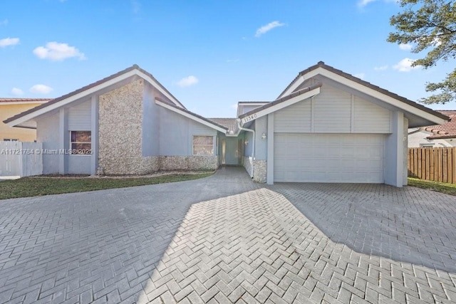 11340 SW 1st St, Coral Springs, FL 33071 - view of front facade featuring stucco siding, decorative driveway, fence, stone siding, and an attached garage