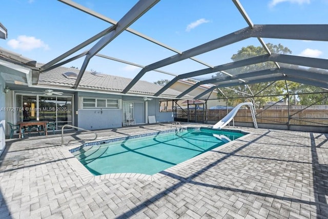 view of swimming pool featuring ceiling fan, a patio area, glass enclosure, and a water slide