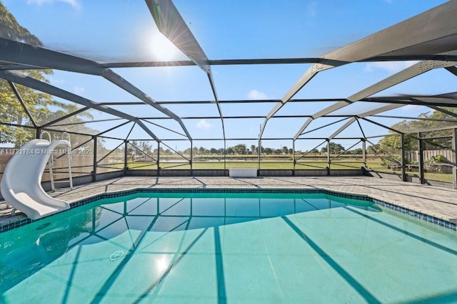 view of pool featuring a water slide, glass enclosure, and a patio area