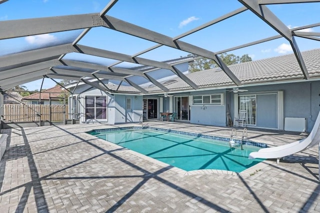 view of swimming pool featuring ceiling fan, a water slide, a lanai, and a patio