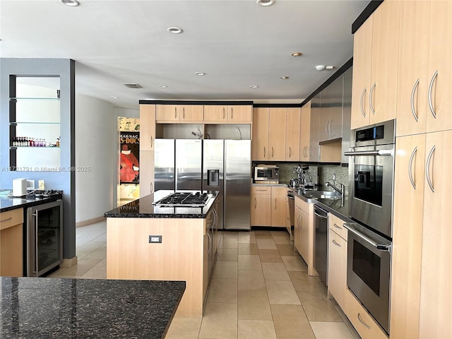 kitchen featuring a center island, light brown cabinets, beverage cooler, stainless steel appliances, and dark stone countertops