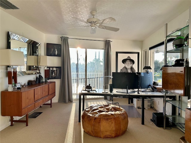 carpeted home office featuring ceiling fan, a healthy amount of sunlight, and a textured ceiling