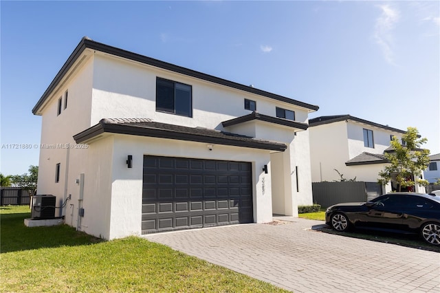 view of front of house with a garage, central air condition unit, and a front yard