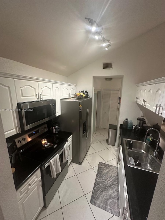 kitchen featuring white cabinets, sink, vaulted ceiling, light tile patterned floors, and stainless steel appliances