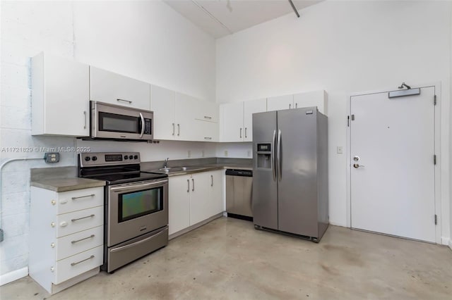 kitchen featuring white cabinets, sink, a towering ceiling, and stainless steel appliances