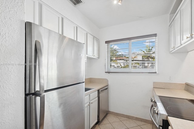 kitchen featuring white cabinets, light tile patterned floors, and stainless steel appliances