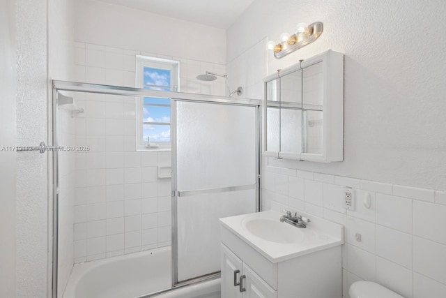 full bathroom featuring vanity, shower / bath combination with glass door, backsplash, toilet, and tile walls