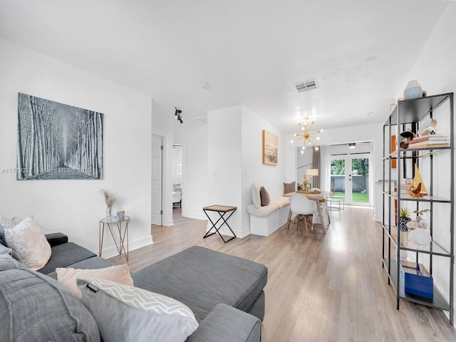 living room featuring french doors, light wood-type flooring, and a notable chandelier