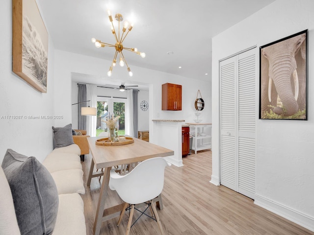 dining space featuring ceiling fan with notable chandelier and light hardwood / wood-style flooring