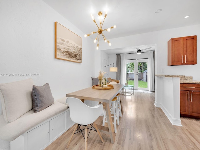 dining space featuring french doors, ceiling fan with notable chandelier, and light hardwood / wood-style flooring