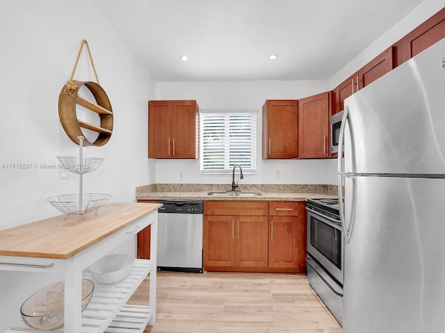 kitchen with wooden counters, sink, stainless steel appliances, and light wood-type flooring