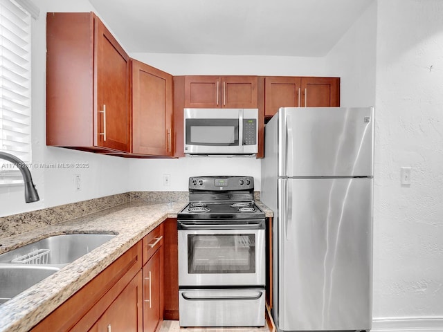 kitchen with plenty of natural light, light stone counters, sink, and appliances with stainless steel finishes