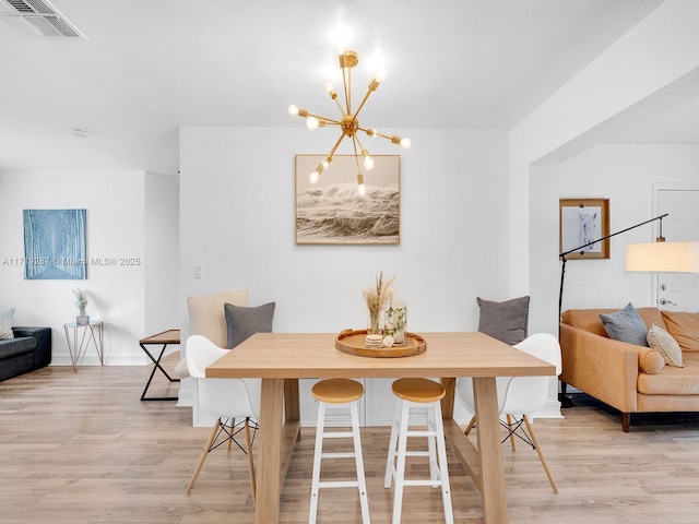 dining space featuring light wood-type flooring and a chandelier