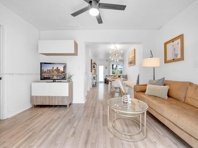 living room with ceiling fan with notable chandelier and light hardwood / wood-style flooring