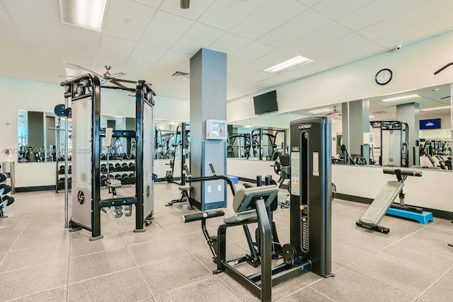 gym with a paneled ceiling, visible vents, and baseboards