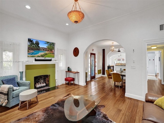 living room with a wealth of natural light, hardwood / wood-style floors, a notable chandelier, and ornamental molding