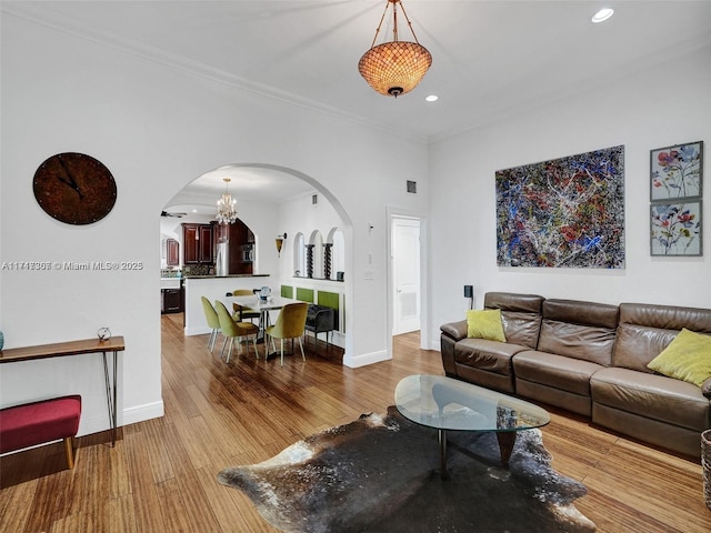 living room featuring a chandelier, crown molding, and light hardwood / wood-style flooring