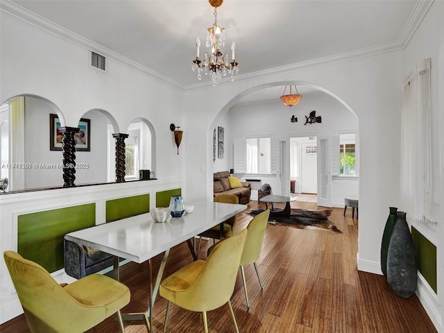 dining space featuring hardwood / wood-style flooring, a notable chandelier, and ornamental molding