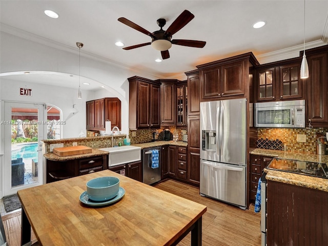 kitchen with tasteful backsplash, light stone counters, decorative light fixtures, and appliances with stainless steel finishes