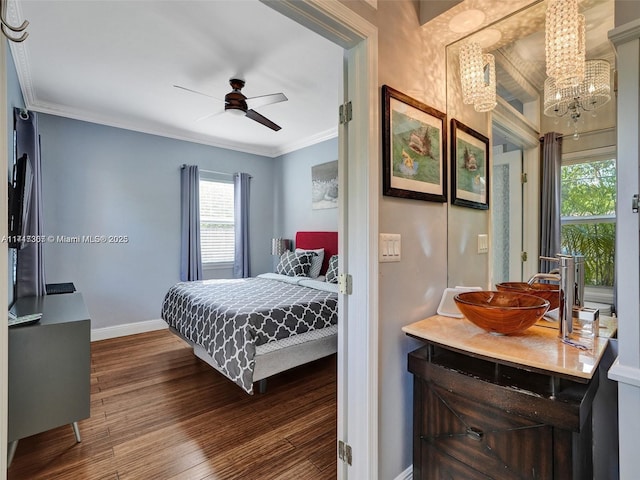 bedroom with crown molding, sink, dark hardwood / wood-style floors, and ceiling fan with notable chandelier