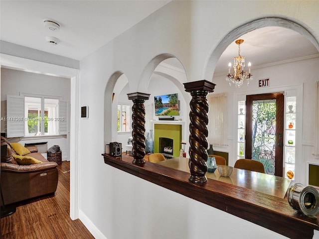 dining room with ornate columns, crown molding, dark hardwood / wood-style flooring, and an inviting chandelier