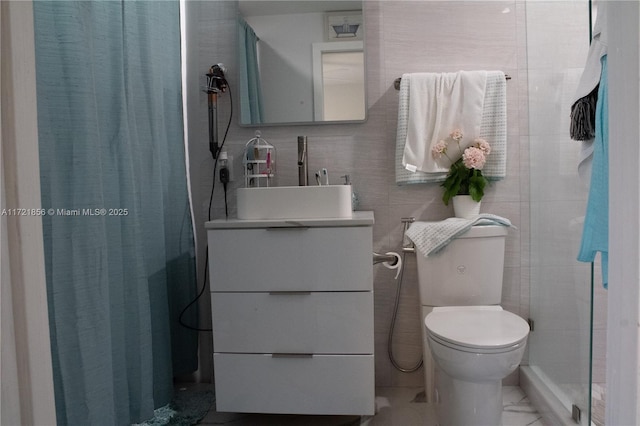 bathroom with a shower, vanity, toilet, and tile walls