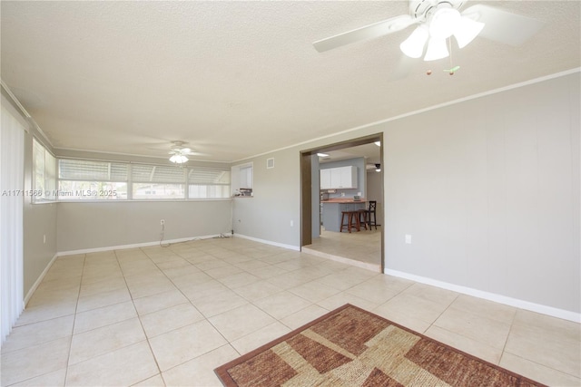 spare room featuring light tile patterned flooring, ceiling fan, crown molding, and a textured ceiling