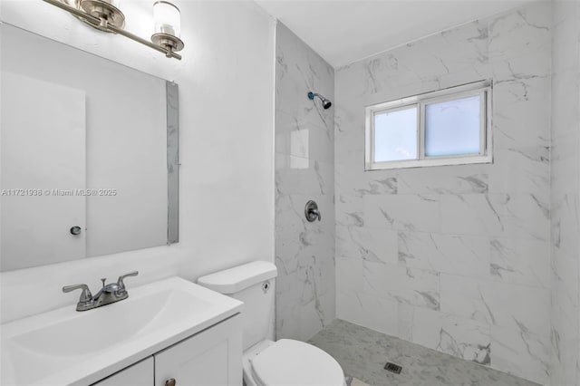 bathroom with tiled shower, vanity, and toilet