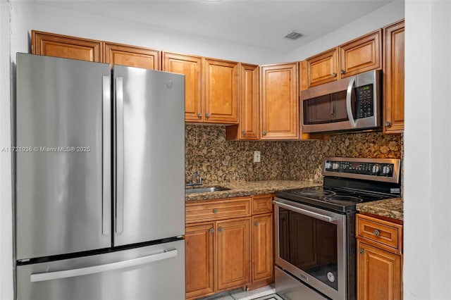 kitchen featuring dark stone counters, appliances with stainless steel finishes, tasteful backsplash, and sink