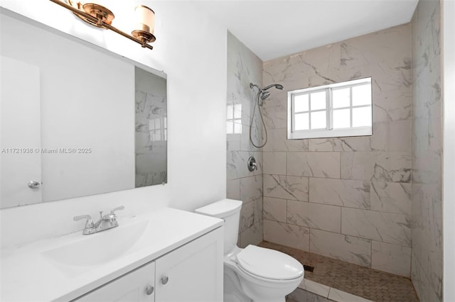 bathroom featuring toilet, tiled shower, and vanity