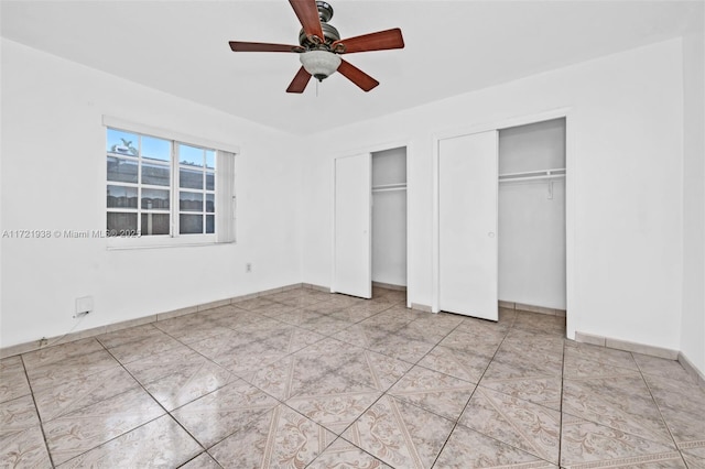 unfurnished bedroom featuring multiple closets and ceiling fan