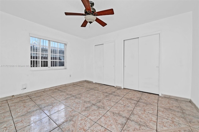 unfurnished bedroom featuring ceiling fan, light tile patterned floors, and multiple closets