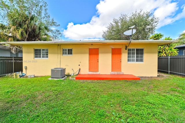 rear view of house featuring central AC and a yard