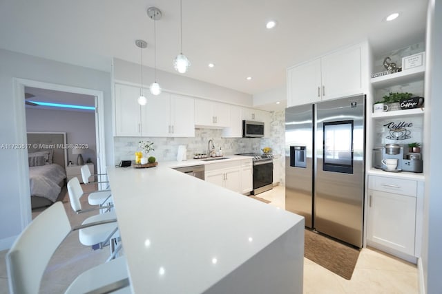 kitchen with white cabinetry, appliances with stainless steel finishes, decorative light fixtures, and sink