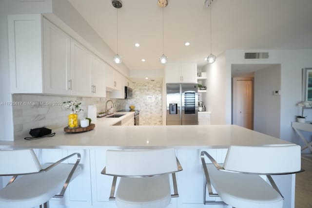 kitchen featuring pendant lighting, sink, stainless steel appliances, and white cabinets