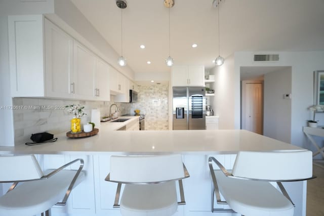kitchen with open shelves, stainless steel fridge, a peninsula, light countertops, and decorative backsplash