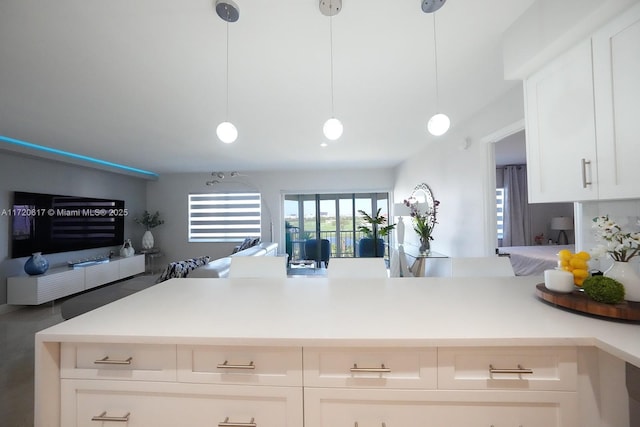 kitchen with a peninsula, hanging light fixtures, light countertops, white cabinetry, and open floor plan