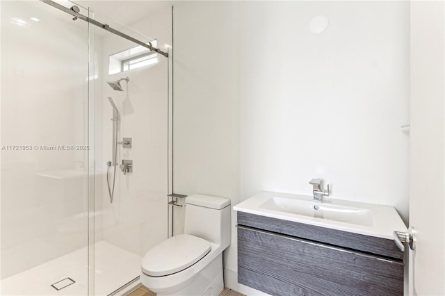 bathroom featuring vanity, a shower with shower door, and toilet