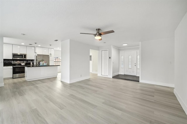 unfurnished living room with ceiling fan, a textured ceiling, and light hardwood / wood-style flooring