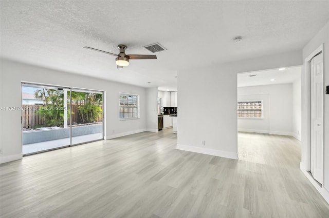 unfurnished living room featuring ceiling fan, light hardwood / wood-style flooring, and a textured ceiling