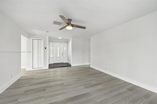 unfurnished living room with hardwood / wood-style flooring, ceiling fan, and a textured ceiling