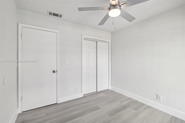 unfurnished bedroom with ceiling fan, a closet, and light hardwood / wood-style flooring