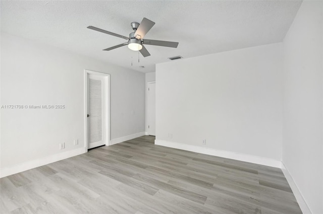 unfurnished room with a textured ceiling, light hardwood / wood-style flooring, and ceiling fan