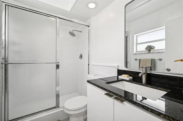 bathroom featuring vanity, toilet, and a shower with shower door