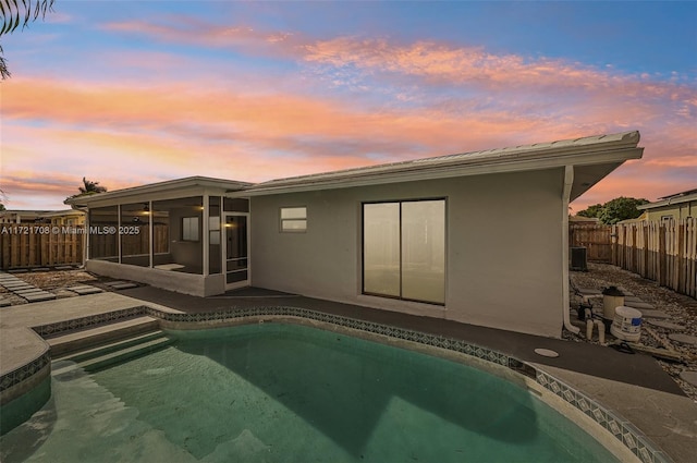 pool at dusk with a sunroom