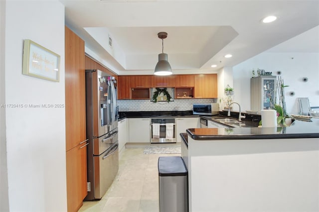 kitchen featuring pendant lighting, a raised ceiling, sink, kitchen peninsula, and stainless steel appliances